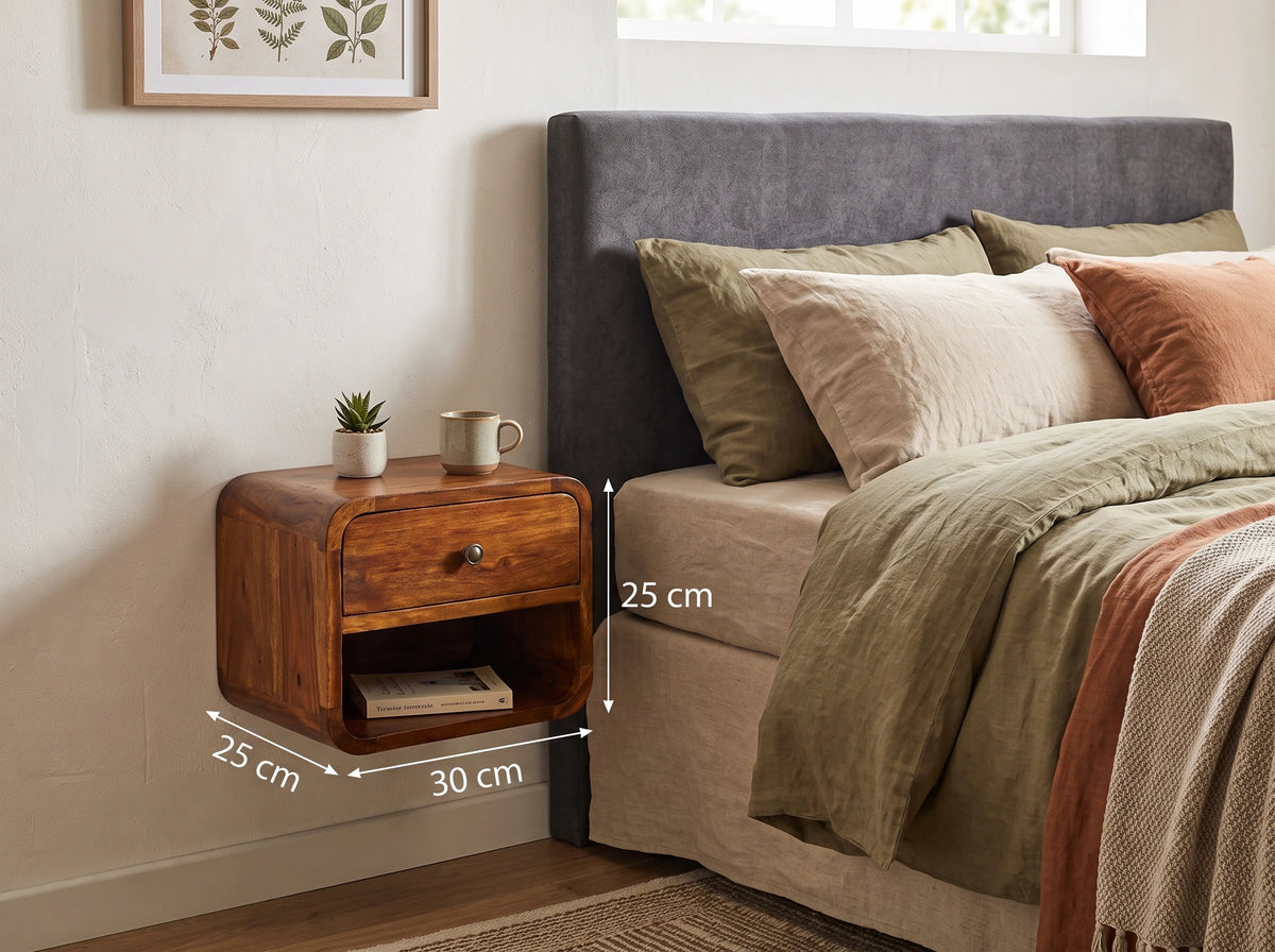 Lifestyle image of a chestnut solid mango wood floating curved bedside table wall-mounted next to a bed, with dimension overlays indicating 30 cm width, 25 cm depth, and 25 cm height.