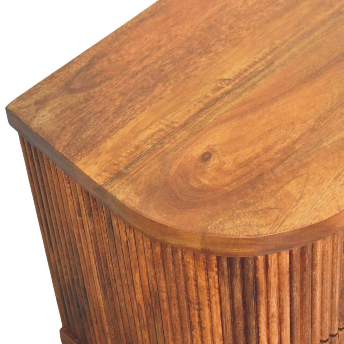 Elevated angled view showing the smooth solid mango wood top surface and rounded edges of a ribbed bedside table in amber oak.