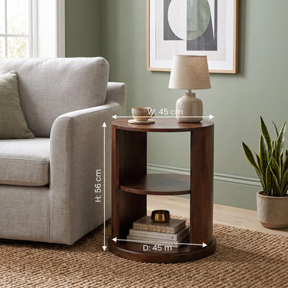 A dark brown wooden side table shown in a living room setting next to a grey armchair, with overlaid dimension lines indicating a width of 45 cm, height of 56 cm, and depth of 45 cm.