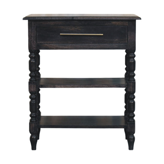 Front view of a solid mango wood turned-leg side table in a carbon ash finish, featuring a single drawer with a brass handle and two open lower shelves.