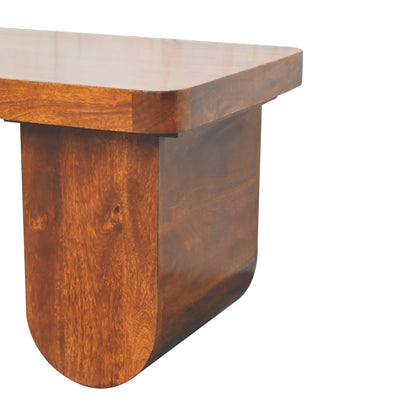 Close-up detail of the smooth, rounded bottom edge of the chunky solid wood leg on a chestnut mango wood coffee table.