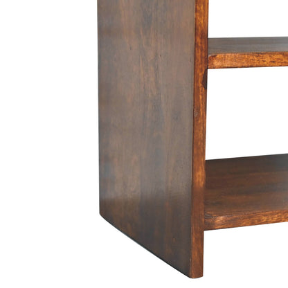 Detail shot of the bottom left corner of a chestnut bedside table, showing the solid wood side panel acting as the legs and the bottom shelf.