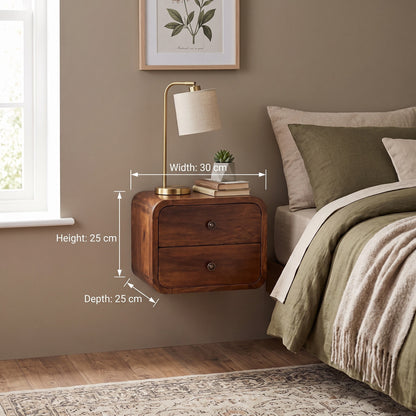 A floating wooden nightstand with two drawers is shown beside a bed in a styled bedroom. White dimension lines and text indicate the nightstand's measurements: 30 cm width, 25 cm height, and 25 cm depth.