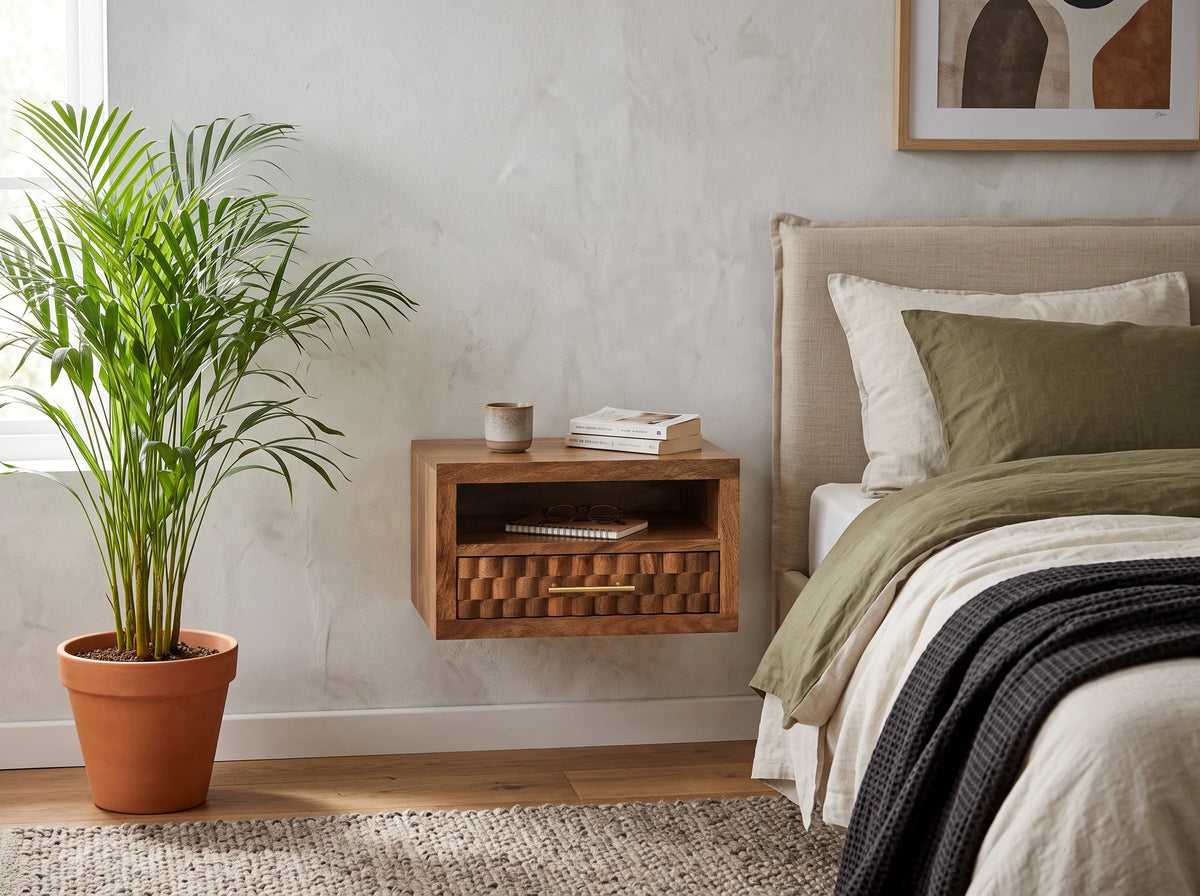 Lifestyle image of a golden teak solid mango wood wall-mounted bedside table next to a bed.