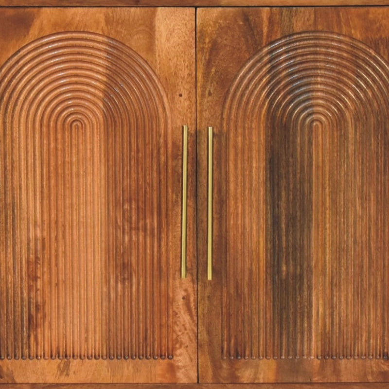 A pair of warm medium-brown wooden cabinet doors featuring a carved concentric arch pattern and fitted with slim vertical brass handles.