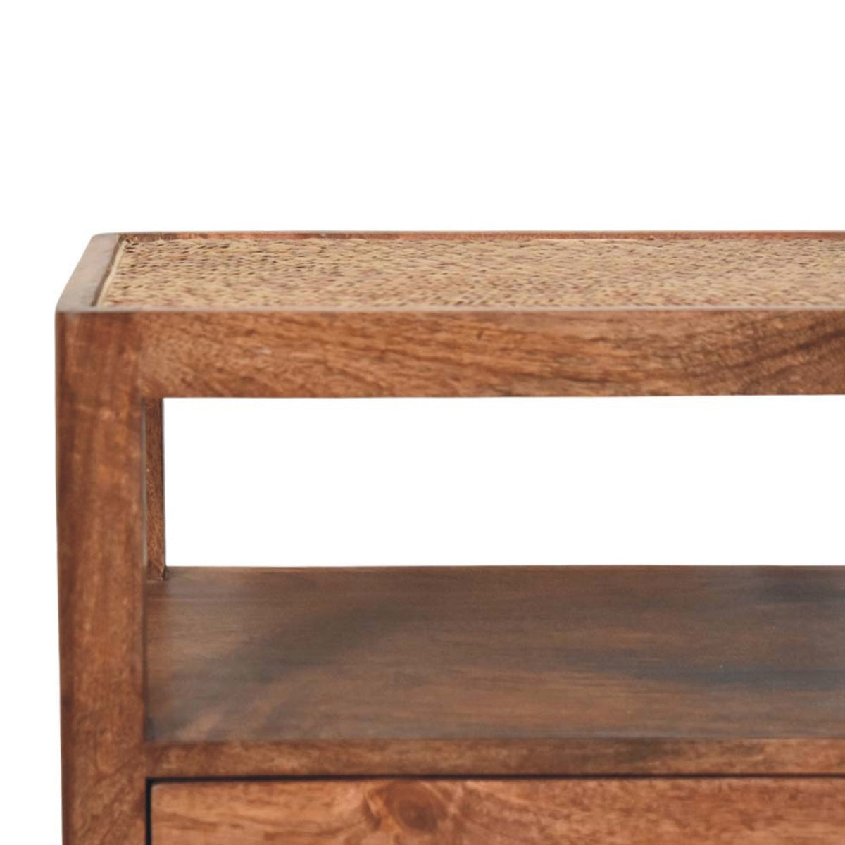 Close-up detail of the open shelf and the woven rattan top inset into the honey caramel solid mango wood frame of a bedside table.