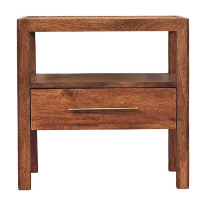 Front view of a solid mango wood bedside table in honey caramel, featuring a woven rattan top, an open shelf, and a single drawer with a brass handle.