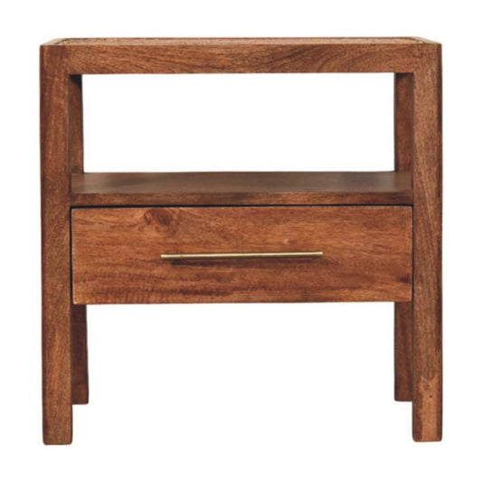 Front view of a solid mango wood bedside table in honey caramel, featuring a woven rattan top, an open shelf, and a single drawer with a brass handle.