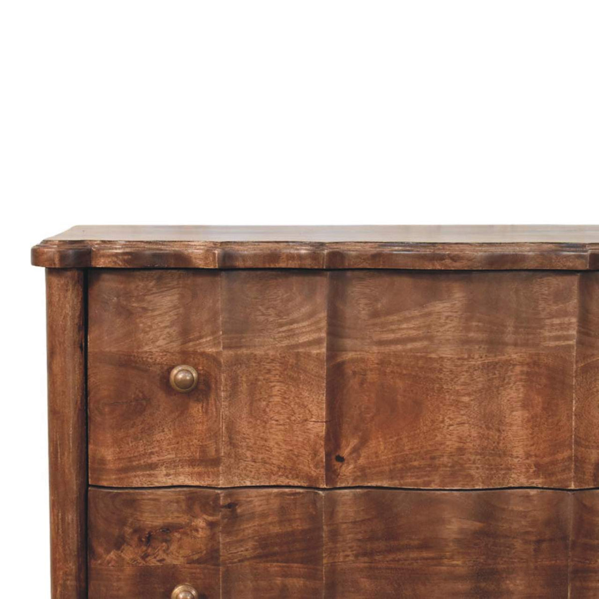 Close-up of a panelled solid mango wood chest in roasted almond, highlighting the scalloped top edge, the wavy vertical paneling on the drawers, and a metal knob.