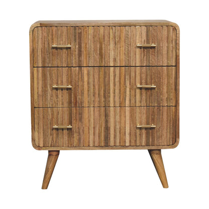 Front view of a three-drawer solid mango wood chest in a natural oak finish, featuring ridged drawer fronts, rounded corners, and brass handles.