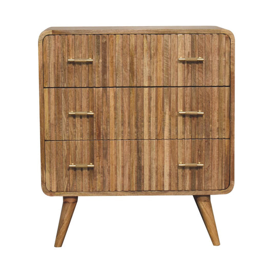 Front view of a three-drawer solid mango wood chest in a natural oak finish, featuring ridged drawer fronts, rounded corners, and brass handles.