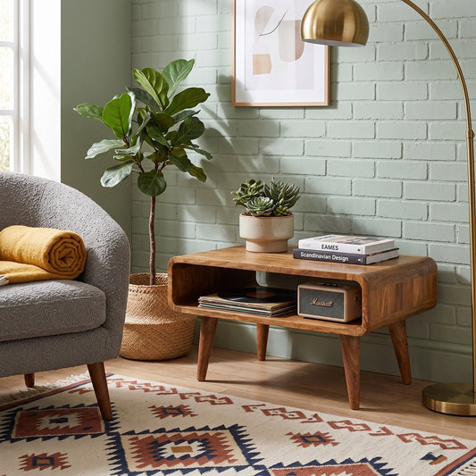 A mid-century modern wooden media unit with an open shelf, styled in a cozy living room next to a gray armchair, a potted fiddle-leaf fig, and a brass floor lamp.