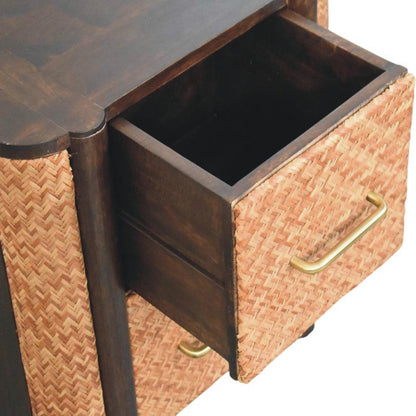 High-angle view showing the top drawer pulled open on a rattan and mango wood bedside table in velvet mocha, revealing the dark wooden interior.