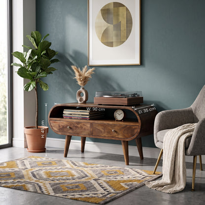 A mid-century modern wooden media console in a styled living room setting, featuring a plant, armchair, rug, and wall art. White dimension lines overlay the product showing its width of 90 cm and depth of 35 cm.