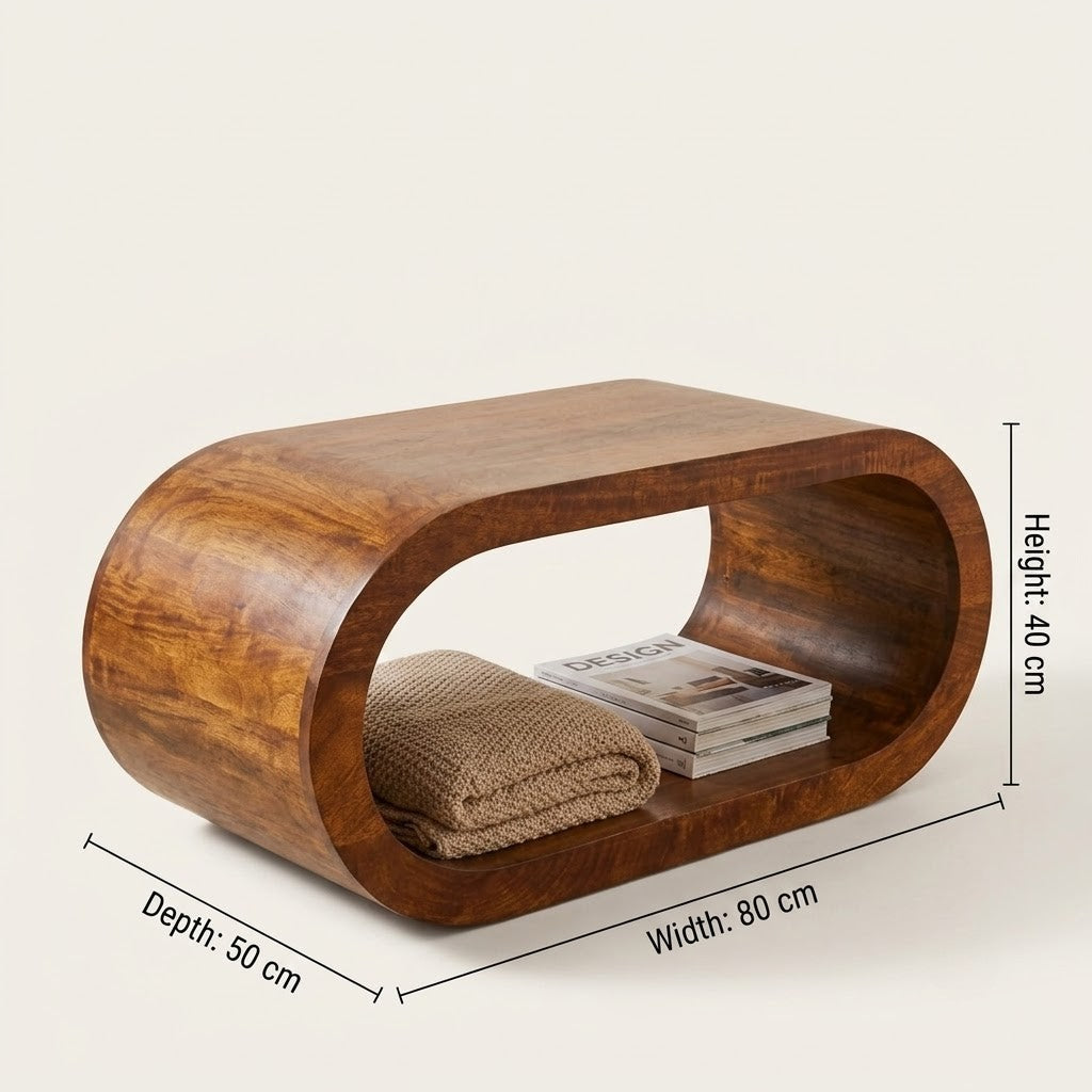 Curved wooden coffee table with a warm medium-brown finish, shown on a light beige background with overlaid dimension labels indicating depth 50 cm, width 80 cm, and height 40 cm. A folded beige knit blanket and a stack of magazines rest inside the open shelf.