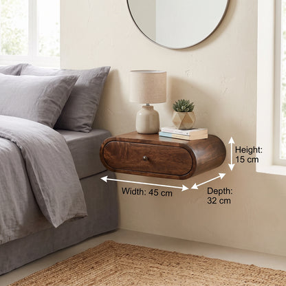 A floating wooden nightstand with a single drawer is shown mounted on a beige wall beside a bed. White dimension arrows label the product measurements as width 45 cm, depth 32 cm, and height 15 cm.