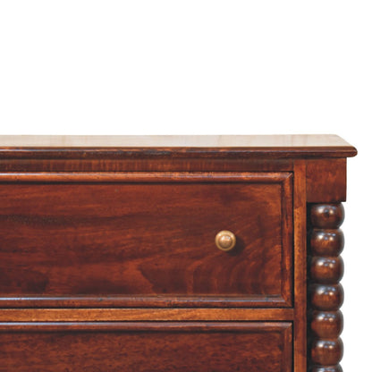 Close-up detail of the top right corner of the Winewood Oak chest, showing the smooth wood grain, a brass drawer knob, and the turned spindle column.