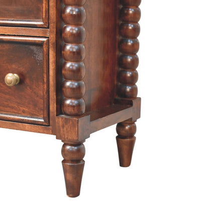 Close-up detail of the bottom right corner of the chest, showcasing the base of the spindle column and the tapered turned wooden foot.