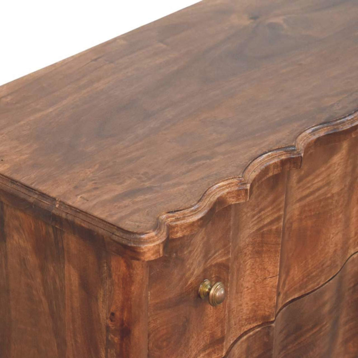 Detail shot emphasizing the rich wood grain on the top surface and the distinctive scalloped front trim of a mango wood chest.