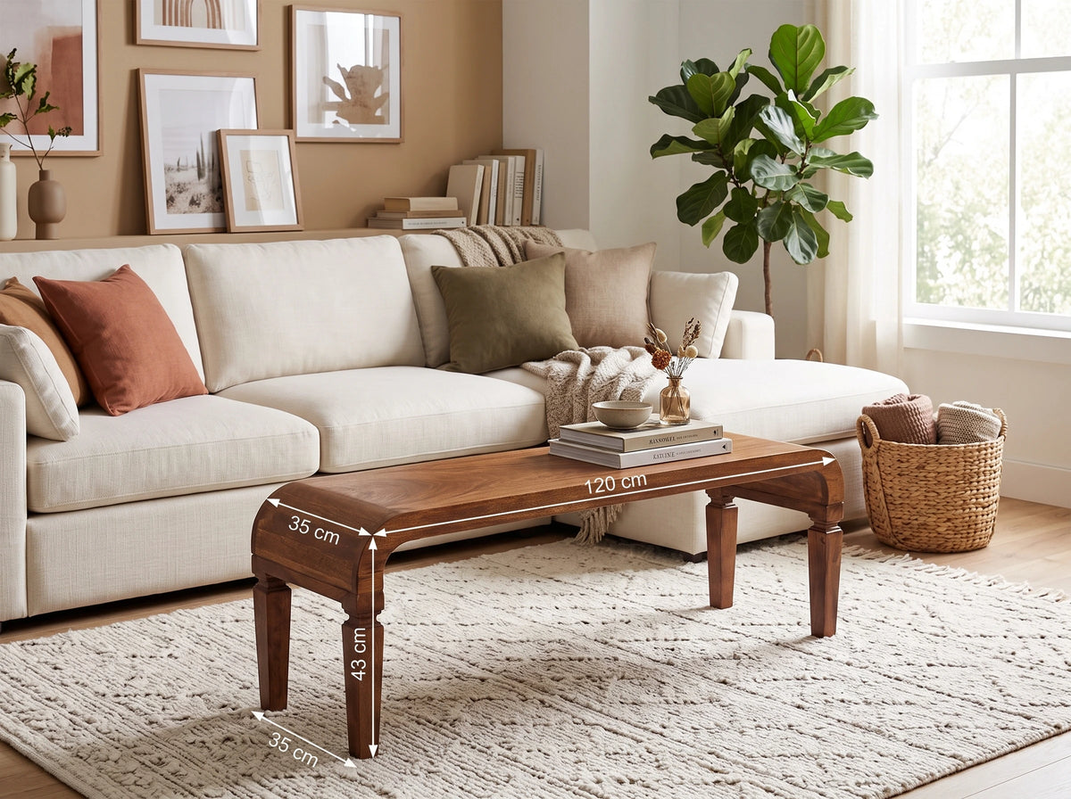 Solid mango wood coffee table in a warm amber oak finish, styled in a bright living room in front of a modern white sofa. White dimension lines and text overlay the table showing measurements of 120 cm length, 35 cm width, 45 cm leg height, and 30 cm base width.