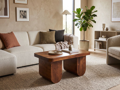 A solid mango wood chunky coffee table in a chestnut finish, styled in a warm living room in front of a textured cream sofa.