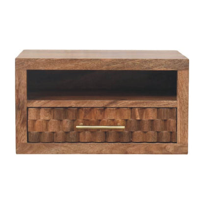 Front view of a solid mango wood floating bedside table in golden teak, featuring an open shelf above a single drawer with a geometric textured front and brass handle.