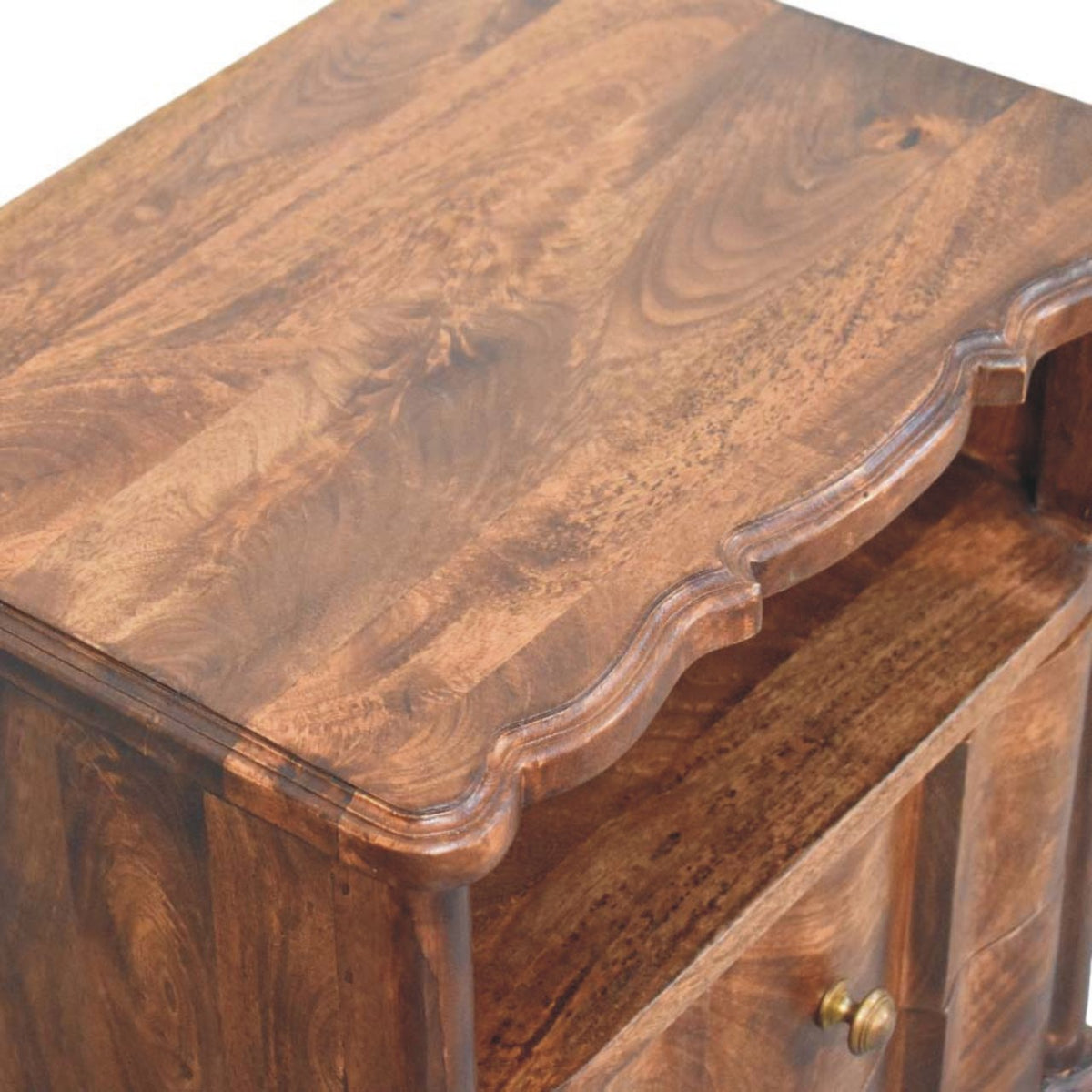 Elevated close-up angled view emphasizing the scalloped front edge of the top surface on a roasted almond mango wood bedside table.