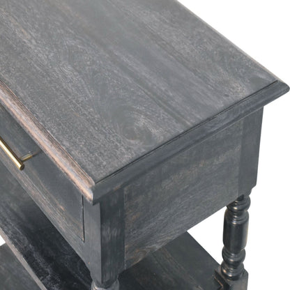 Elevated angled view showing the smooth top surface and upper drawer of a solid mango wood side table in a carbon ash finish.