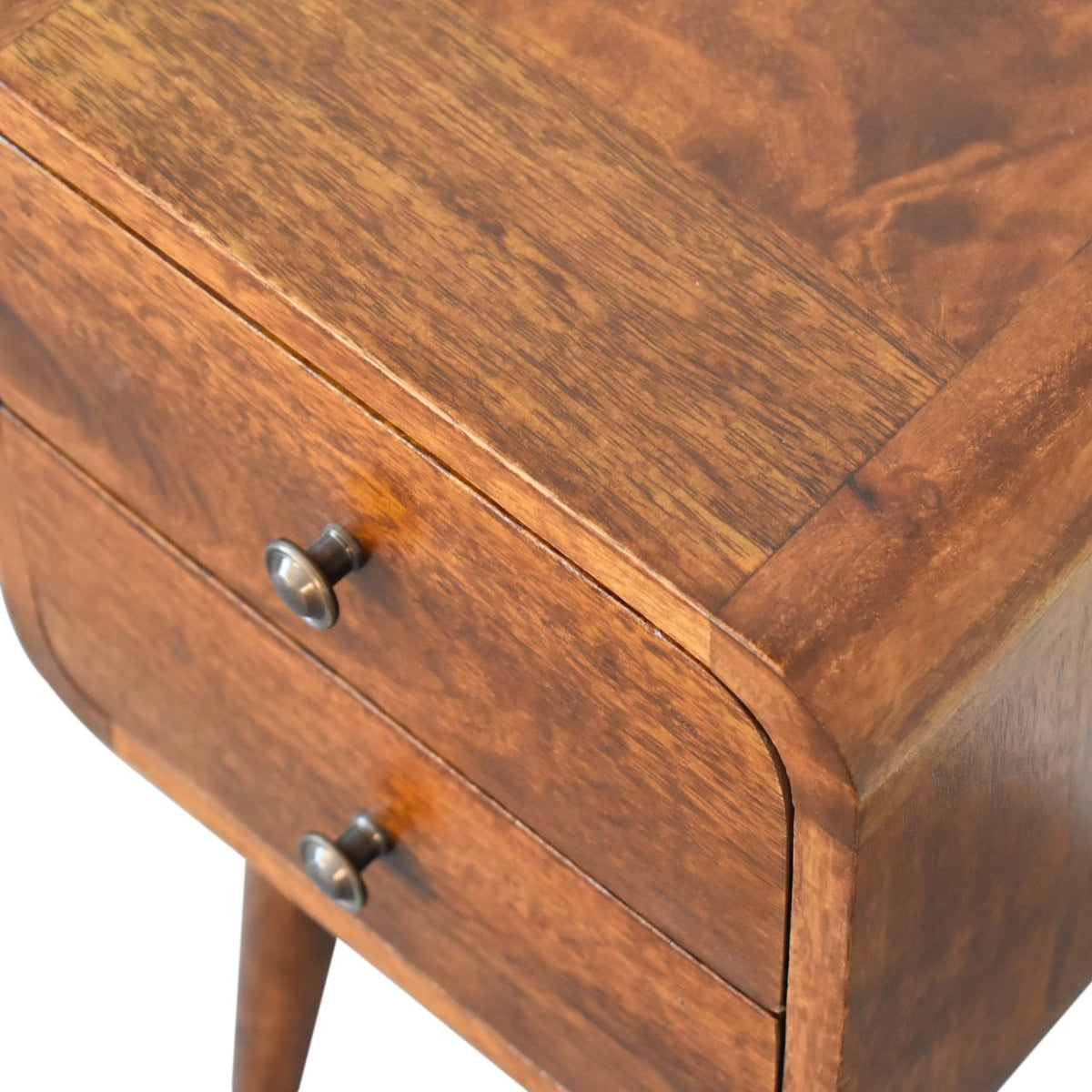 Close-up of a wooden bedside table with two drawers and metal handles.