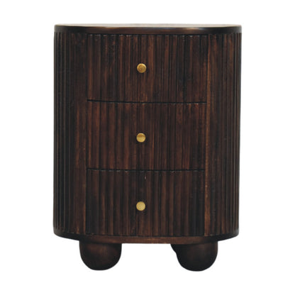 Front view of a solid mango wood curved bedside table in velvet mocha, featuring a vertical fluted texture, three drawers with small brass knobs, and round bun feet.