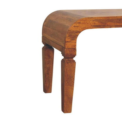 Close-up of the curved corner joinery and top of the carved leg on an amber oak mango wood coffee table.