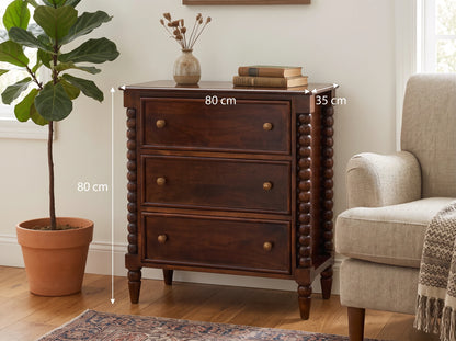 Lifestyle image of a Winewood Oak solid mango wood 3-drawer spindle chest next to an armchair, with dimension overlays indicating 80 cm width, 35 cm depth, and 80 cm height.
