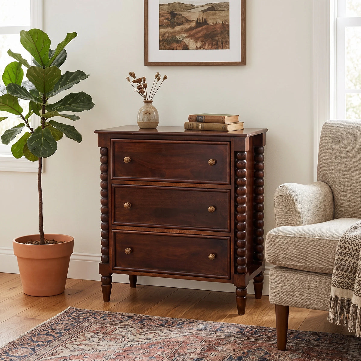 Lifestyle image of a Winewood Oak solid mango wood 3-drawer spindle chest next to an armchair.
