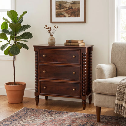 Lifestyle image of a Winewood Oak solid mango wood 3-drawer spindle chest next to an armchair.